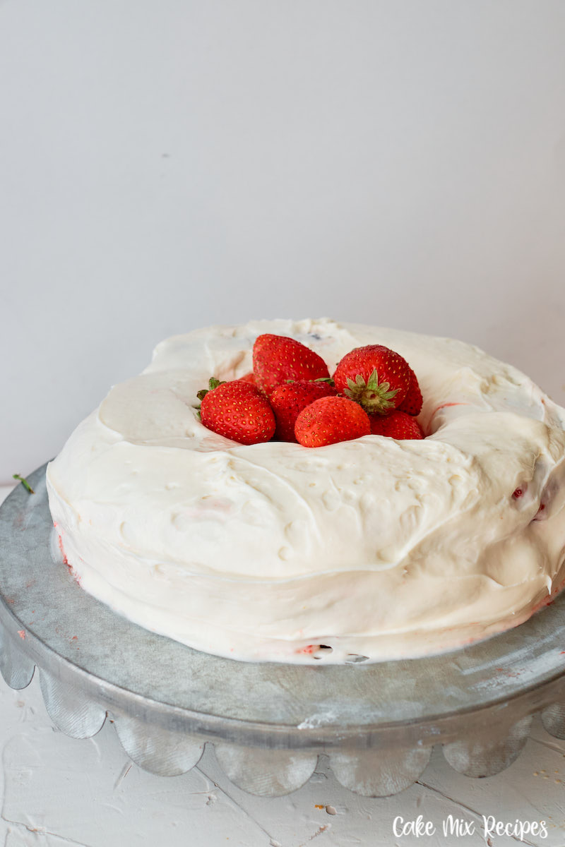 The whole cake with icing and strawberries on top ready to cut and serve. 