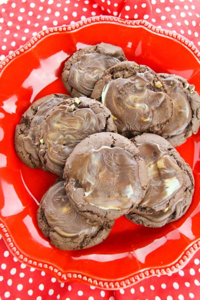 A red plate with a batch of chocolate mint cookies on top.