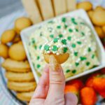 Featured image showing the finished shamrock dunkaroo dip held up on a cookie to eat.