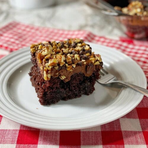A slice of the chocolate caramel poke cake on a checkered table cloth.