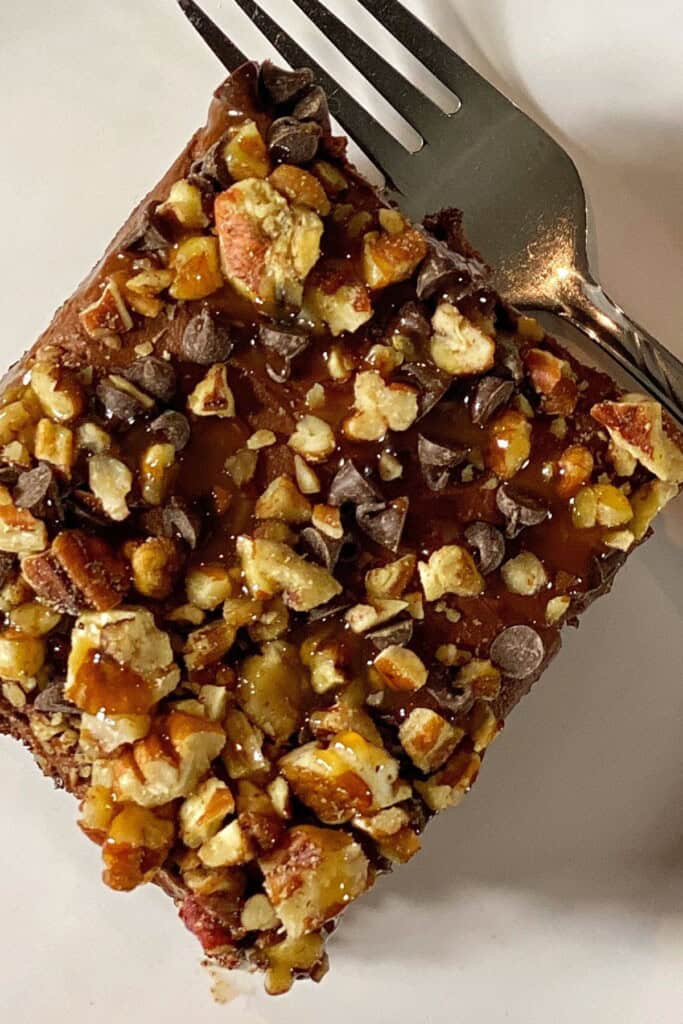A slice of the chocolate caramel poke cake on a white plate.