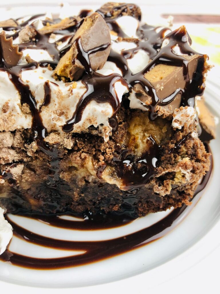 a closeup of Chocolate Peanut Butter Dump Cake on a plate drizzled with chocolate syrup.