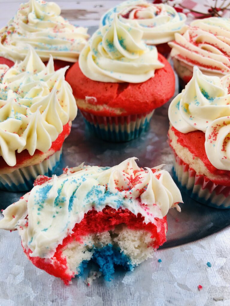 patriotic cupcakes with one cut open so you can see the red white and blue layers inside