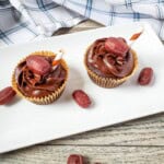 Two chocolate root beer cupcakes on a white tray with root beer barrels on the side.