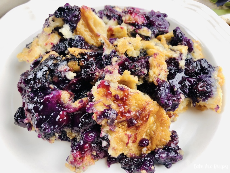 A close up view of the finished dump cake with blueberries ready to eat. 