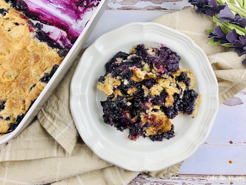 Featured image showing the finished blueberry dump cake served on a plate ready to eat.