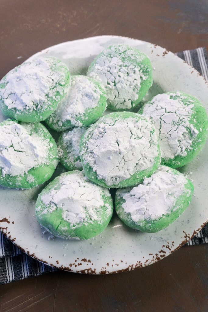 Grinch Sugar Cookies rolled in powdered sugar on a plate. 