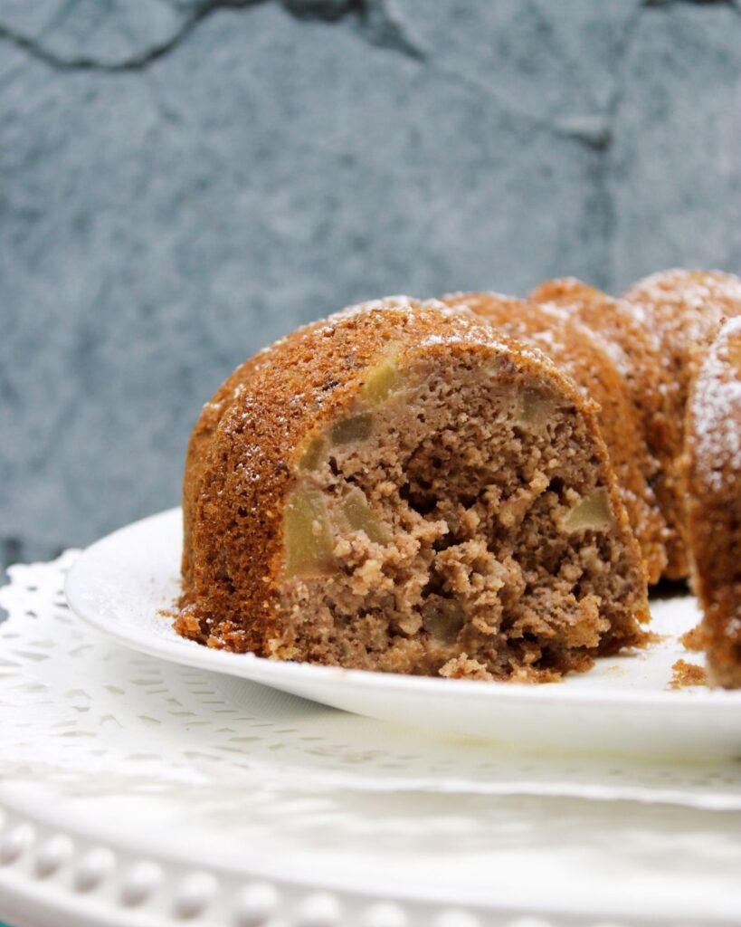 applesauce bundt cake on a white plate with a slice taken out of it