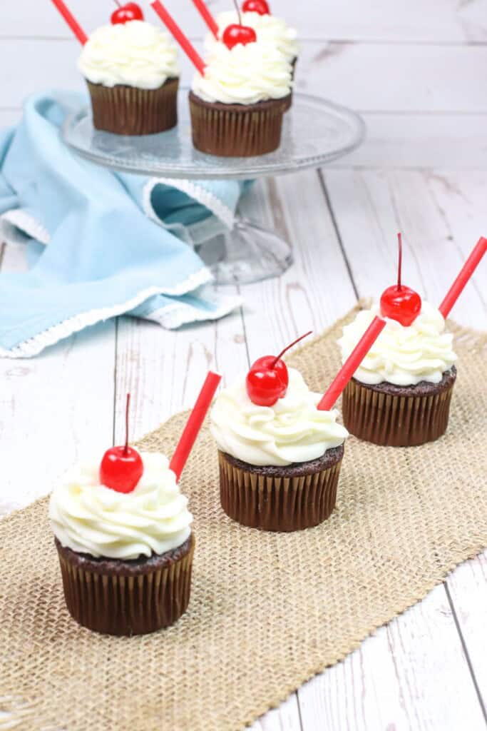 Three treats on a white tray with cherries and straws.
