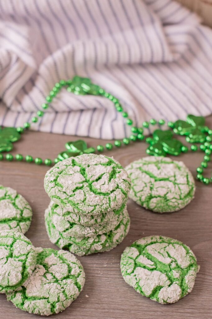 a stack of green vanilla crinkle cookies next to a green necklace and a striped cloth