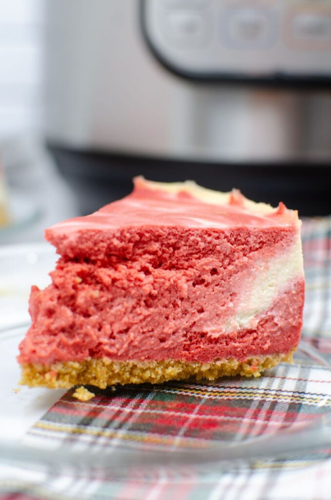 red velvet instant pot cheesecake on a glass plate with an instant pot blurred in the background