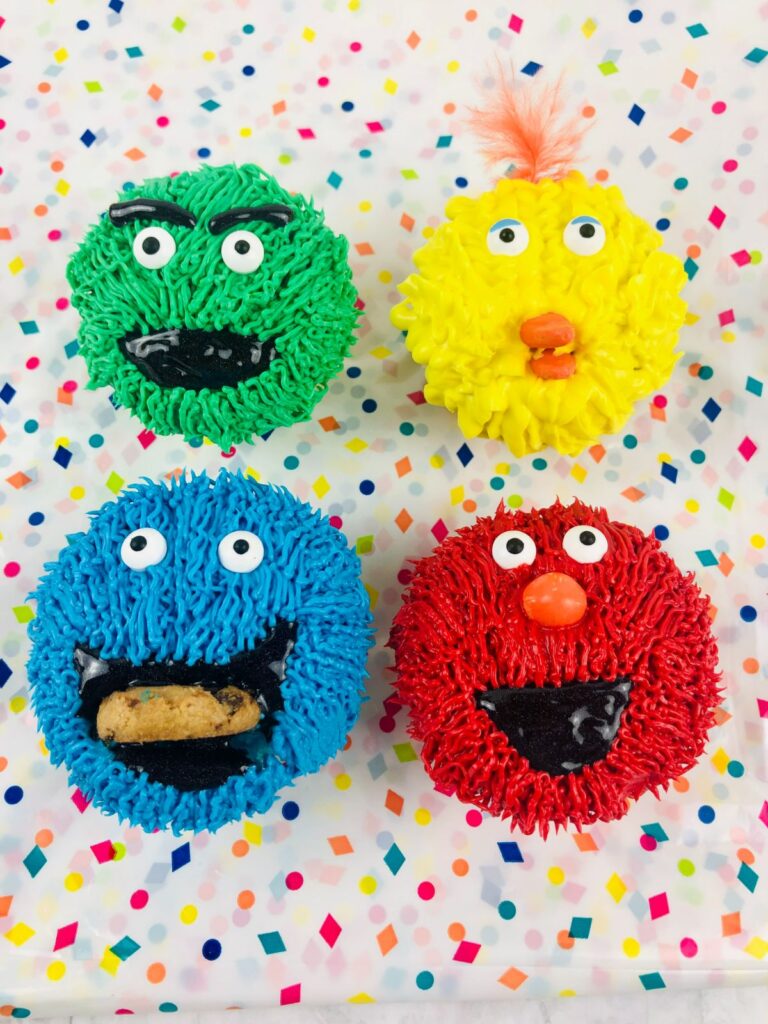 4 Sesame Street Cupcakes decorated to look like Oscar, Big Bird, Cookie Monster and Elmo