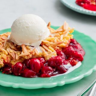 cherry dump cake on a green plate and topped with vanilla ice cream