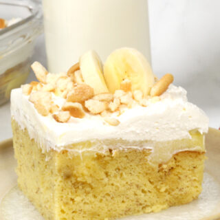 banana cream poke cake topped with frosting and fresh banana slices