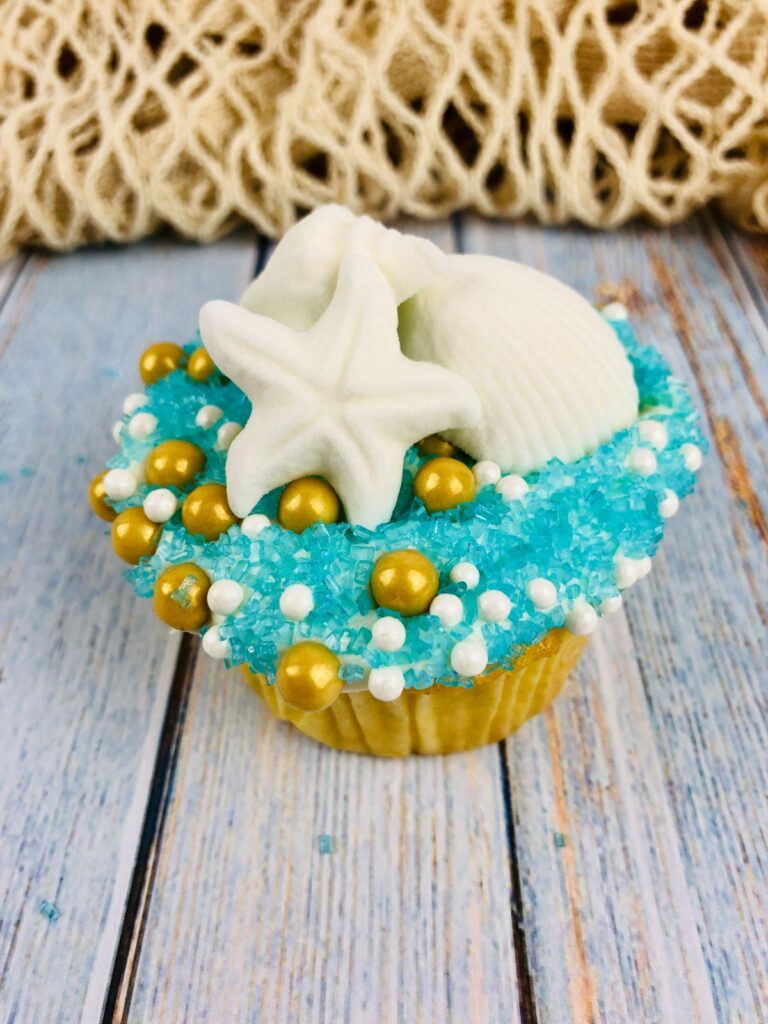beach cupcake on a wood table with a net behind it