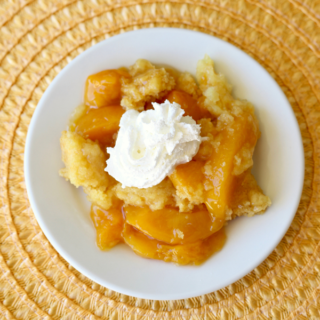 crock pot peach dump cake served on a plate with whipped cream