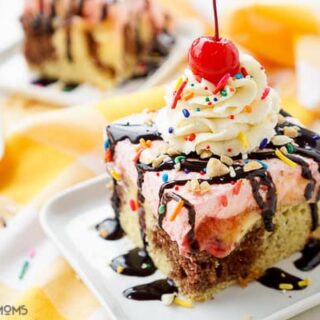 banana split poke cake topped with whipped cream, rainbow sprinkles, chocolate sauce, and a cherry