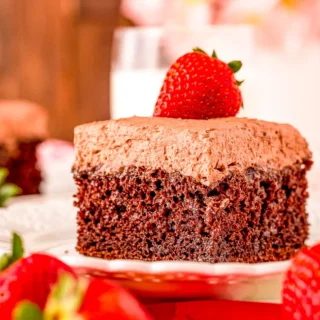 chocolate poke cake topped with chocolate whipped frosting and a whole strawberry