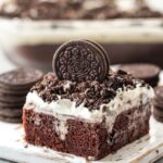 oreo poke cake served on a white plate and garnished with a whole oreo