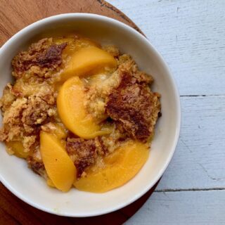 peach dump cake served in a dish and topped with peach slices