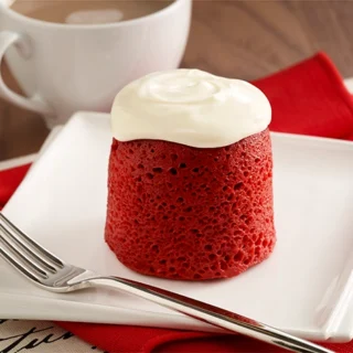 red velvet mug cake with cream cheese frosting served on a plate and with a fork