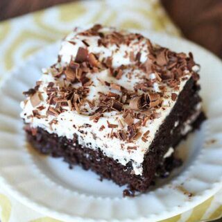chocolate mudslide poke cake topped with vanilla frosting and chocolate pieces