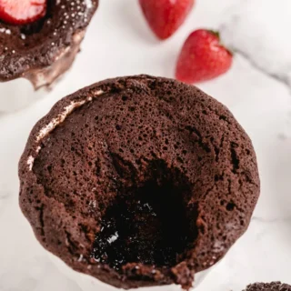 chocolate lava cake served in a dish with a spoon and strawberries on the side