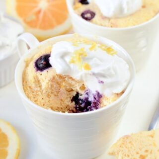 keto lemon mug cake topped with lemon zest and whipped cream