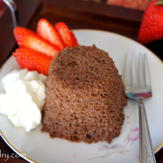 chocolate mug cake with a side of whipped cream and fresh strawberries