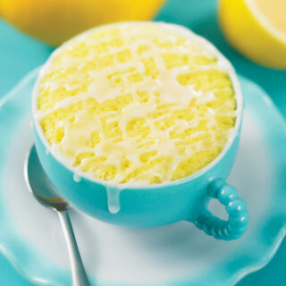 lemon cake in a mug topped with a glaze and served in a blue mug