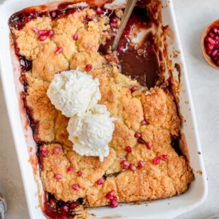 pomegranate apple cobbler with cake mix in a serving dish with vanilla ice cream