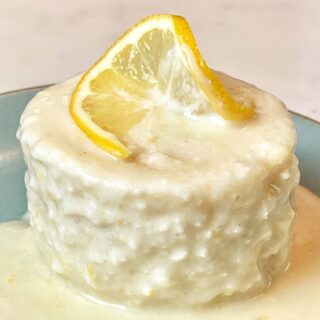 keto lemon mug cake with a lemon glaze and topped with a fresh lemon slice