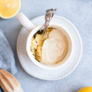 lemon mug cake topped with a glaze and served with a spoon