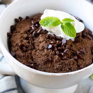 protein chocolate mug cake topped with chocolate chips, whipped cream, and a mint leaf