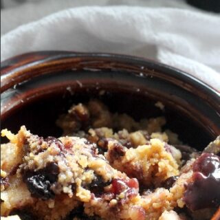 blueberry dump cake in a small brown bowl on top of cloth napkins