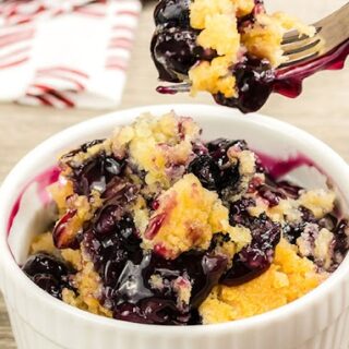 Blueberry Dump Cake in glass bowl with small piece on fork