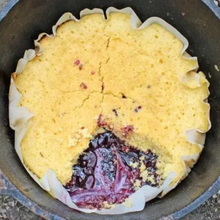 Lemon Blueberry Dump Cake in a round cast iron skillet, with a slice missing