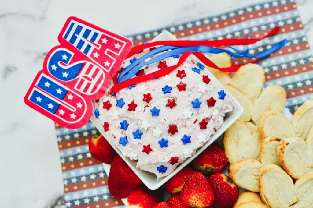 A Tray of patriotic cake mix dip with fruit on the side.