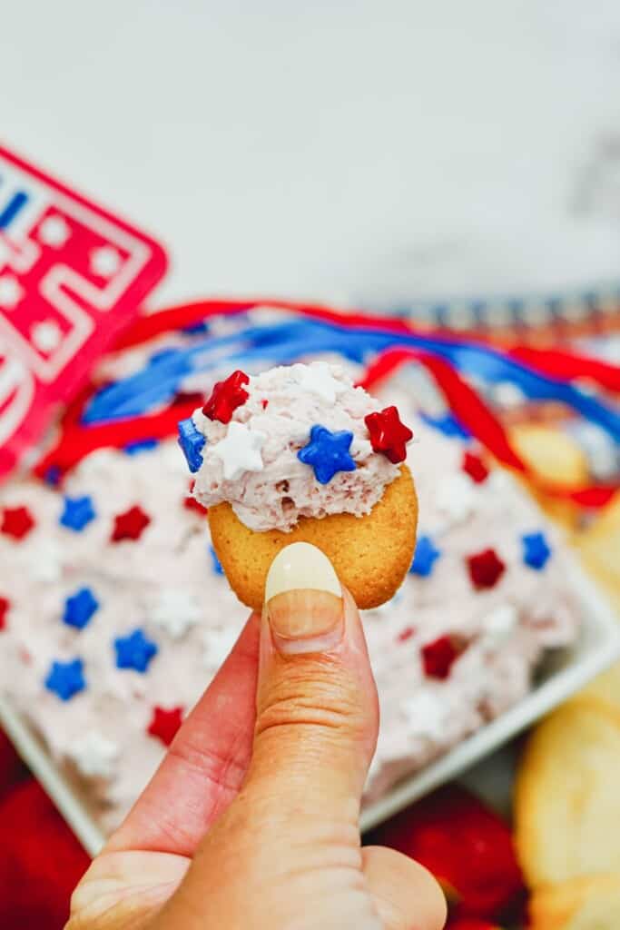 The finished recipe smeared on a cookie with a hand holding it.