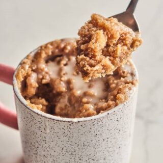 crumbly sweet coffee mug cake in a mug with a piece taken out on a spoon