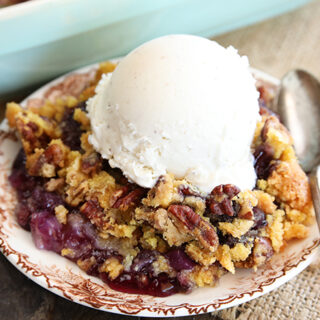 Pineapple Blueberry Dump Cake on a plate with a spoon and vanilla ice cream on top
