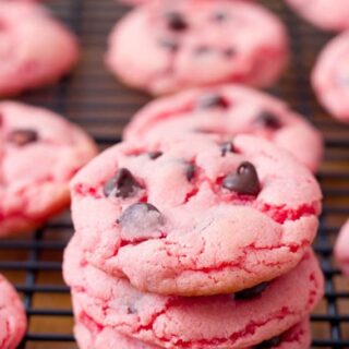 Strawberry Chocolate Chip Cake mix cookies stacked on top of one another with others in the background
