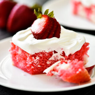 Strawberry Jell-o Poke Cake with icing and sliced strawberries on top