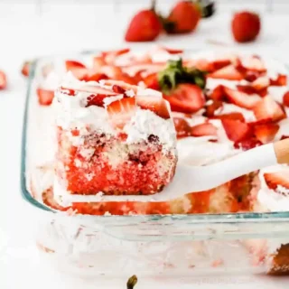 Strawberry Jello Poke cake with white icing and fresh sliced strawberries on top