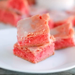 two pink Strawberry Cake MIx brownies stacked on top of one another with more in the background