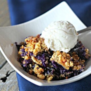 Blueberry Dump Cake with vanilla ice cream on top in a white dish