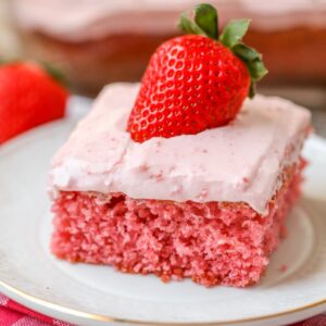 Piece of strawberry sheet cake with pink frosting and fresh strawberry on top