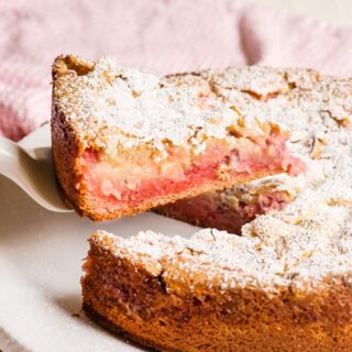 Strawberry cake with slice pulled out, with powdered sugar on top