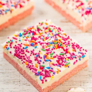 strawberry cookie bars with icing and rainbow sprinkles on top