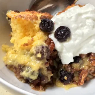 blueberry dump cake with walnuts in a white bowl with a spoon